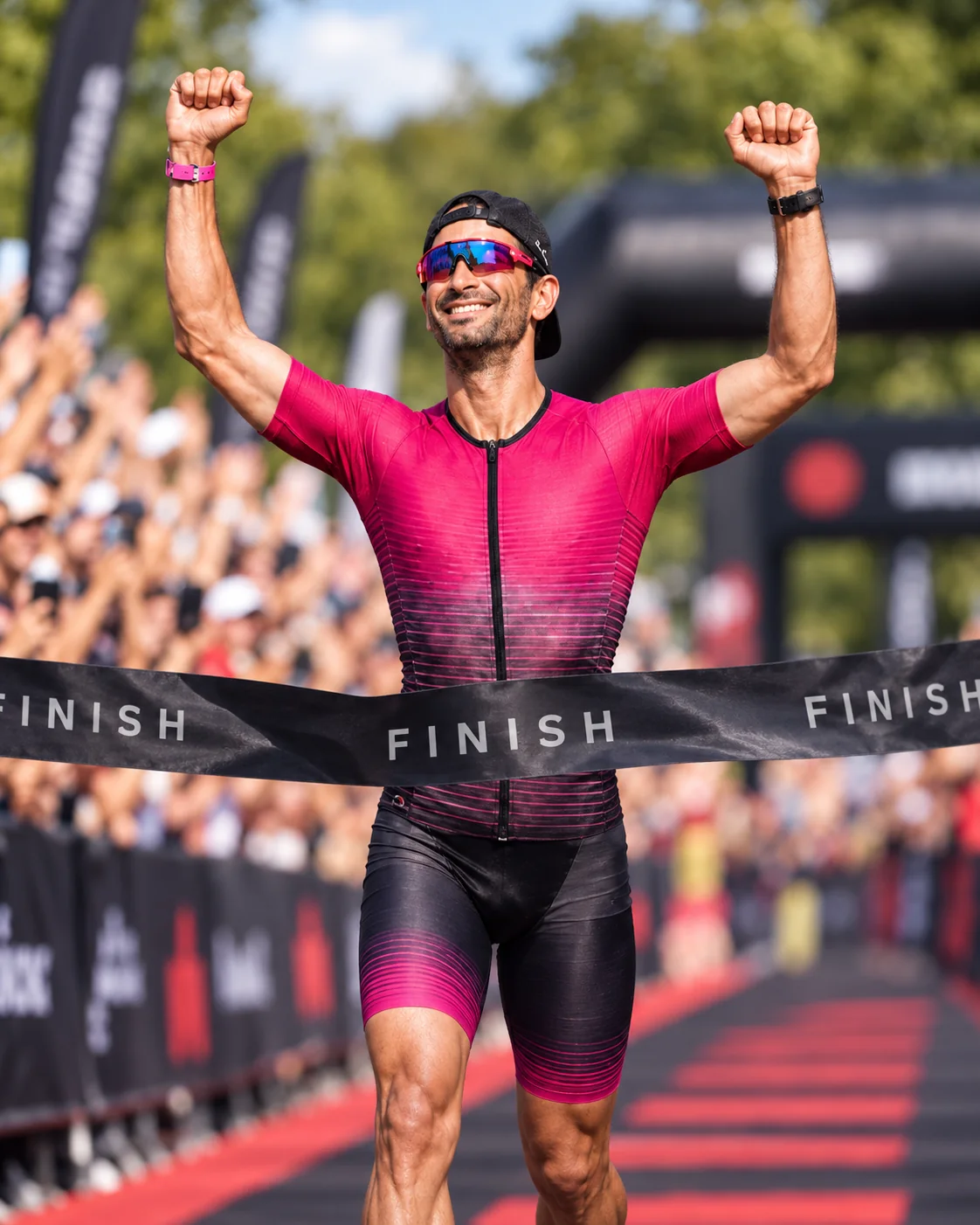 Navin smiling with raised arms while crossing the finish tape
